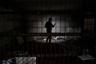 Украинский военнослужащий стоит в подвале, где, как утверждают украинские власти, пытали людей