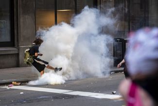 Протестующий откидывает газовую гранату обратно в полицейских. 30 мая 2020 года