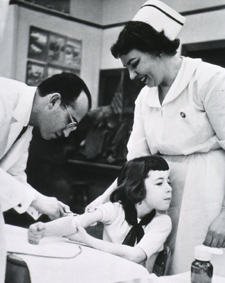Джонас Э. Солк, американский врач, разработавший первую эффективную вакцину против полиомиелита, прививает ребенка. Около 1955 года