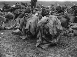 Немецкие военнопленные кутаются в водонепроницаемые накидки на берегу Рейна. 28 марта 1945 года