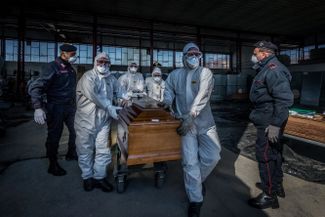 Медики и карабинеры переносят гробы с телами умерших из-за коронавируса в Бергамо, 24 марта 2020 года