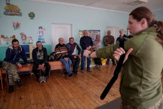 Фельдшер ВСУ показывает служащим территориальной обороны, как остановить кровотечение с помощью жгута, недалеко от линии фронта на севере Киевской области