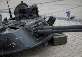 Ребенок рассматривает башню взорванной бронемашины — она составляет часть экспозиции уничтоженной российской техники, которую устроили в центре Киева