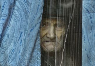 Пожилой мужчина смотрит из окна автобуса