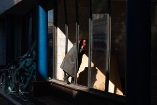 Женщина заглядывает внутрь здания сквозь разбитое окно. Киев