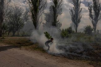 Житель Донецкой области пытается потушить загоревшуюся после обстрела траву в районе Дружковки