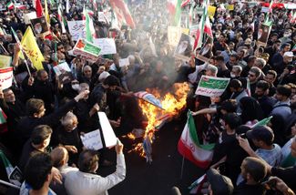 Демонстранты, поддерживающие правительство Ирана, сжигают флаги США, Израиля и Великобритании. Тегеран, 25 сентября 2022 года