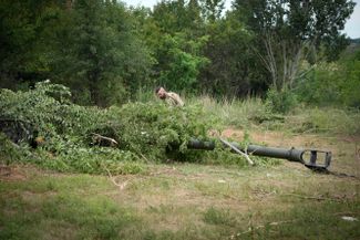 Украинский солдат маскирует американскую гаубицу M777 перед тем, как открыть огонь по российским позициям