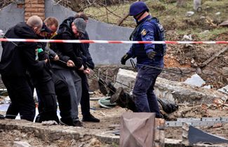 Полицейские достают тело мирного жителя из колодца на заправке в селе Бузовая Киевской области. По словам главы села, мужчина был убит российскими солдатами.