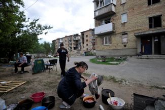 Жительница Мощуна Киевской области готовит обед на костре. Село сильно пострадало от российских артиллерийских обстрелов и во время оккупации, там до сих пор отсутствуют электроснабжение и газ<br>