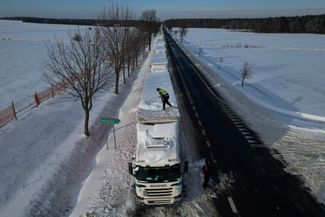 Водитель счищает снег с крыши грузовика в очереди на КПП «Хребенне — Рава Руска» на польско-украинской границе