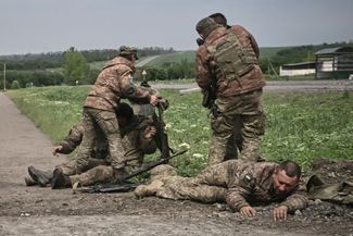 Украинские военнослужащие помогают своим раненым товарищам недалеко от линии фронта в Донбассе