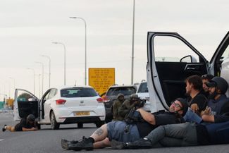 Журналисты укрываются за автомобилями, когда израильские военные занимают позиции в бою с палестинскими боевиками у границы сектора Газа. 7 октября 2023 года
