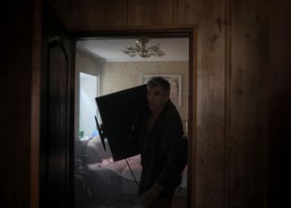Владимир выносит телевизор из своего дома, который загорелся в результате одного из ракетных ударов по Константиновке