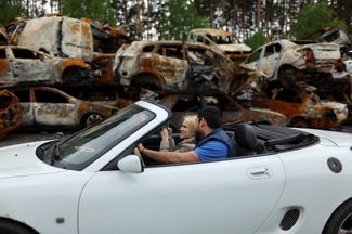 Пара на территории свалки машин, поврежденных и уничтоженных в результате обстрелов, Буча