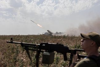 Украинский солдат прикрывает позиции артиллеристов ВСУ, пока те ведут огонь по окопам российских войск под Бахмутом