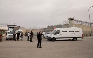 Автобусы с палестинскими заключенными прибывают на территорию военной тюрьмы Офер на Западном берегу Иордана, 25 ноября 2023 года. Там израильские спецслужбы передают освобождаемых палестинцев сотрудникам Красного Креста, а те вывозят их на палестинские территории.