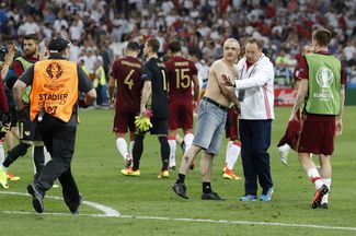 Тренер сборной России Леонид Слуцкий вместе с болельщиком, выбежавшим на поле после матча. 11 июня 2016 года.