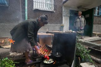 Жители Мариуполя готовят еду во дворе одного из жилых домов, поврежденных в результате обстрела