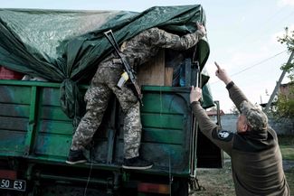 Украинские солдаты укрывают кузов грузовика брезентом