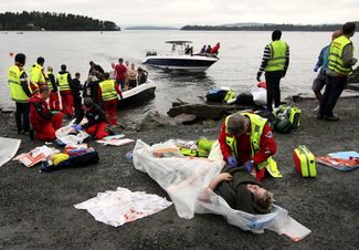 Спасатели оказывают помощь раненой женщине на берегу острова, 22 июля 2011 года