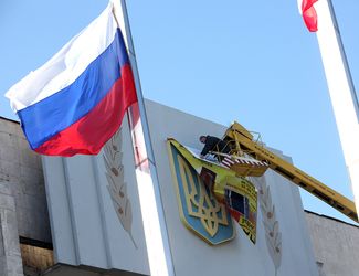 Рабочий заклеивает герб Украины на правительственном здании в Керчи, 20 марта 2014 года