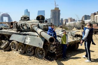 A boy salutes in front of a tank while visiting the Military Trophy Park in Baku, which showcases military equipment seized from Armenian troops during 2020 war over Nagorno-Karabakh. April 15, 2021.