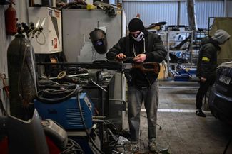 A Ukrainian man fixes a machine gun in an auto repair shop. The weapon was originally in Russian hands