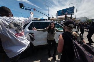 Девушка пытается защитить полицейский автомобиль. Лос-Анджелес, 30 мая 2020 года.