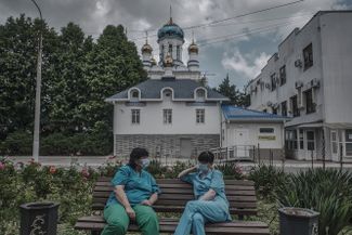 Doctors resting on a bench in front of the building where the entrance to the “red zone” is located
