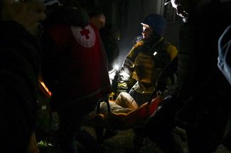 Спасатели несут тело погибшего, найденное среди обломков жилого дома