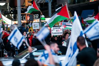 Демонстрант, участвующий в митинге в поддержку Палестины, показывает участникам акции в поддержку Израиля плакат с надписью «Сионизм --это терроризм». США, Нью-Йорк, 13 октября 2023 года