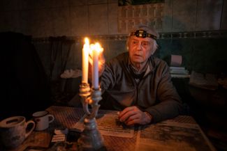 Житель Купянска Владимир Дубровский зажигает свечи в своем доме