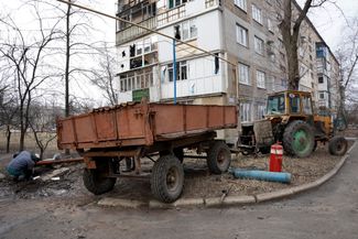 Сварщик чинит газовую трубу у жилого дома, поврежденного во время ночного обстрела оккупированного города Ясиноватая, который расположен в 25 километрах к северу от Донецка