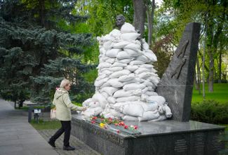 Женщина возлагает цветы к памятнику советскому летчику Ивану Кожедубу в честь Дня Победы во Второй мировой войне. Памятник защищен от обстрелов мешками с песком