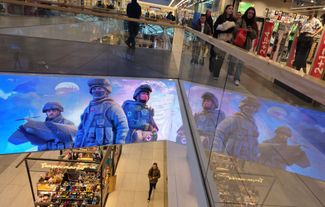 People walk past an army recruitment ad on an electronic screen at a Moscow shopping mall. May 11, 2024.