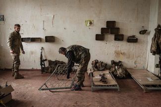 Украинские военные готовят себе спальные места в заброшенном доме, где они отдыхают после двух месяцев боев