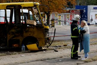 Пожарный в Донецке утешает женщину возле взорванного автобуса, в котором ехал ее сын-подросток