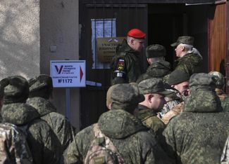 Военнослужащие перед избирательным участком на досрочном голосовании в селе Перевальное, Крым