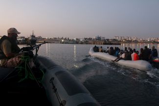 Катер береговой охраны Ливии сопровождает лодку с задержанными мигрантами на базу ВМС Ливии. 20 сентября 2015 года