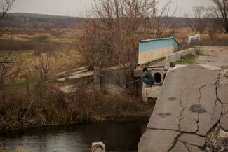 Artem, age 14, fishes on a destroyed bridge in Lebyazhe