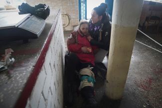 Женщина помогает раненой на рынке в центре города