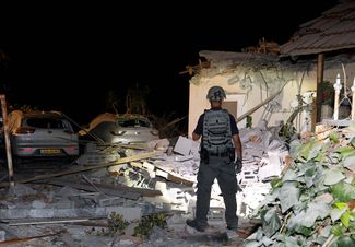 Сотрудник службы безопасности инспектирует разрушенный ракетой дом в пригороде Тель-Авива