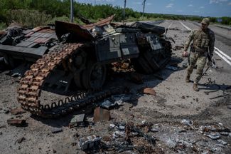 Украинский военнослужащий рядом с уничтоженным украинским танком