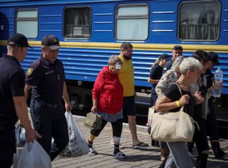 Люди на вокзале готовятся сесть на поезд, следующий из города Днепр во Львов. 16 июля войска РФ <a href="https://www.rbc.ua/rus/news/raketnyy-udar-dnepru-izvestno-etot-moment-1657955409.html" rel="noopener noreferrer" target="_blank">обстреляли</a> завод «Южмаш», который выпускает ракетно-космическую технику. Местные власти сообщали о трех погибших и 16 раненых