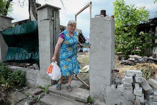 63-летняя Катерина у разрушенных ворот своего дома. Когда весной 2022 года вокруг Богородичного шли ожесточенные бои, Катерина вместе с дочерьми уехала в Святогорск, расположенный в шести километрах. Она вернулась домой в середине мая 2023-го