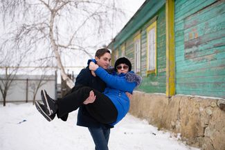Igor Trubnikov carries his mother into their home to keep her off their icy courtyard. December 2018