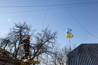 Сотрудники городских служб Киева ремонтируют линии электропередачи, которые были повреждены обломками российской ракеты, упавшей на жилые дома