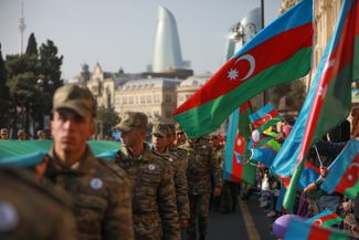 Azerbaijani soldiers carry a giant national flag during a procession marking the anniversary of the end of the 2020 war over Nagorno-Karabakh. Baku, Azerbaijan. November 8, 2021.