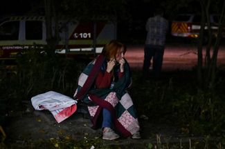Девушка, спасенная из разрушенного ракетными ударами жилого дома, говорит по телефону